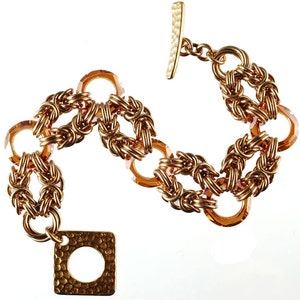 May include: A gold bracelet with a square clasp and amber-colored glass beads. The bracelet is made of a woven chain design.