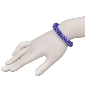 May include: A purple and silver chainmail bracelet on a model's wrist.