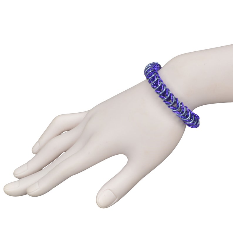 May include: A purple and silver chainmail bracelet on a model's wrist.
