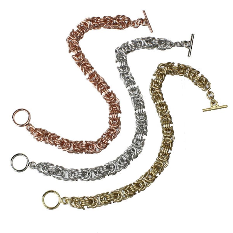 May include: Three chain bracelets in gold, silver, and rose gold. Each bracelet has a toggle clasp.