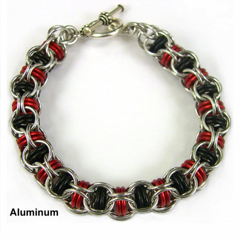 Puede incluir: Un brazalete plateado con anillos negros y rojos. El brazalete est&aacute; hecho de aluminio y tiene un cierre de palanca.