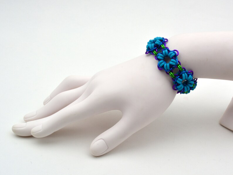 May include: A blue and purple wire bracelet with turquoise flower-shaped beads.