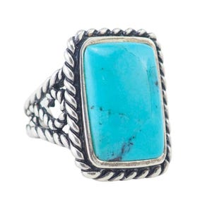 May include: A silver ring with a turquoise stone set in a rope-like design.