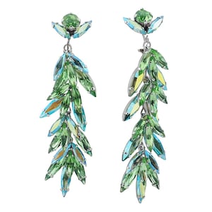 Op de afbeelding: Een paar bungelende oorbellen met een bloemmotief. Elke oorbel heeft een cluster van groene edelstenen aan de bovenkant, met een waterval van groene en blauwgroene bladvormige kristallen eronder. De oorbellen hebben een zilverkleurige metalen zetting.