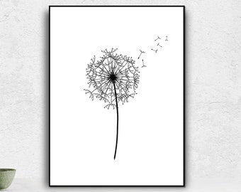 May include: Black and white framed art print featuring a detailed illustration of a dandelion. The dandelion's seed head is depicted with intricate lines, and a few seeds are shown blowing away. The artwork is displayed on a white table with decorative items.