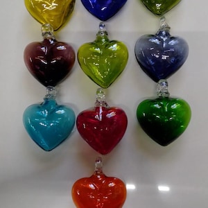 May include: Twelve glass heart ornaments in various colors, including red, green, blue, yellow, and purple. Each heart has a small loop at the top for hanging.