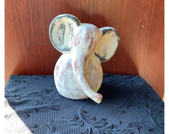 May include: White ceramic elephant figurine with black and brown painted accents. The elephant is facing to the right and has its trunk curled up.