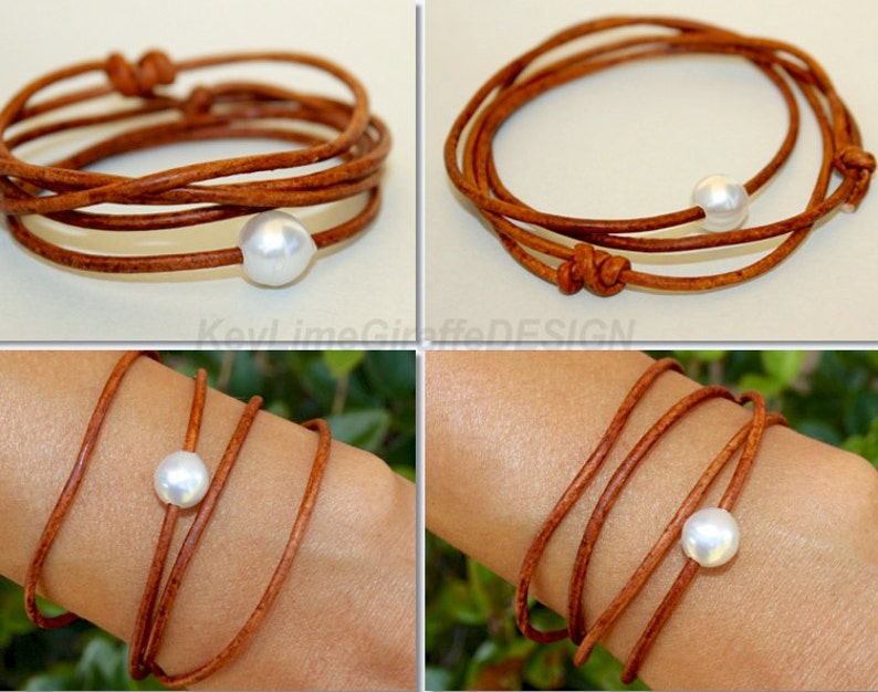 K&ouml;nnte beinhalten: Ein Wickelarmband mit einer gro&szlig;en, wei&szlig;en Perle und mehreren Str&auml;ngen aus braunem Leder. Das Armband ist an den Enden geknotet und wickelt sich mehrmals um das Handgelenk. Das Design ist schlicht und elegant.