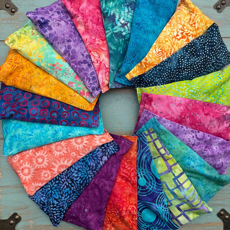 May include: A collection of colorful fabric eye pillows arranged in a circle. The pillows are made from a variety of fabrics, including batik, floral, and geometric patterns.