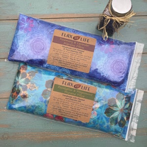 Puede incluir: Dos almohadillas t&eacute;rmicas de semillas de lino con estampado floral azul y blanco. Las almohadillas est&aacute;n etiquetadas como "Flax of Life Rosemary & Lavender Migraine Pillow" y "Flax of Life Eucalyptus & Peppermint Migraine Pillow". Las almohadillas est&aacute;n hechas a mano con semillas de lino y aceites esenciales puros. Las almohadillas se pueden calentar en el microondas durante 50-60 segundos.