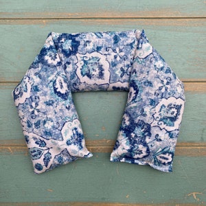 May include: A blue and white patterned neck wrap or pillow. The fabric has a paisley design with a white background and blue and teal accents.
