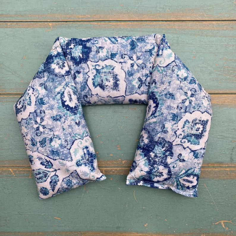 May include: A blue and white patterned neck wrap or pillow. The fabric has a paisley design with a white background and blue and teal accents.