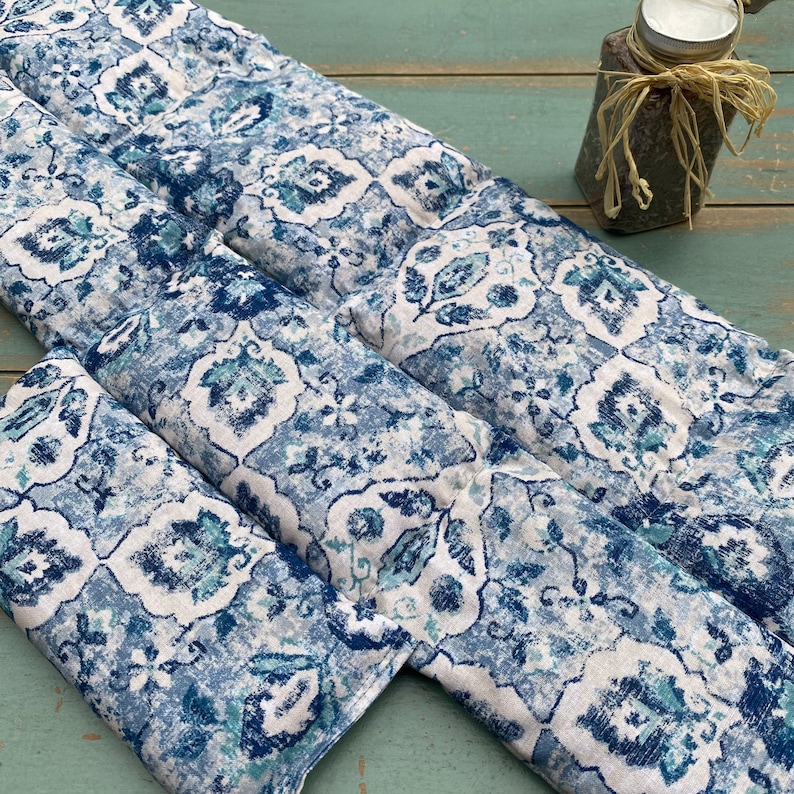 May include: Three blue and white patterned fabric heat packs. The fabric has a paisley design with a white background and blue and green accents.