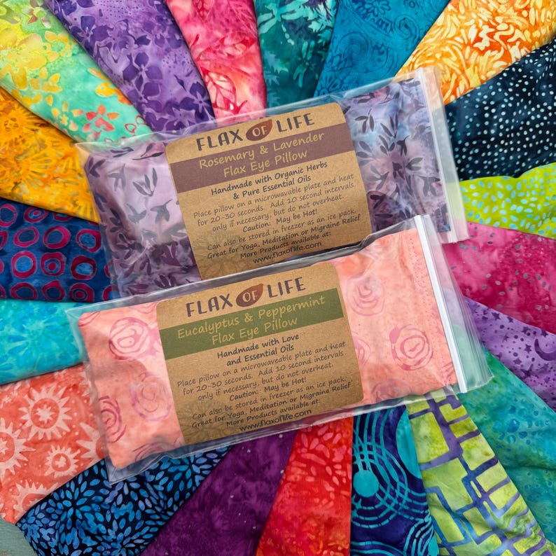 May include: Two flax eye pillows with labels that read "Flax of Life" and feature different essential oils. The pillow on the left is lavender and rosemary, and the pillow on the right is eucalyptus and peppermint. Both pillows are handmade and have a floral print.