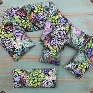 May include: A set of four neck and eye pillows with a succulent floral print. The pillows are made of a soft fabric and are filled with a natural material. The pillows are perfect for relaxing and relieving stress.