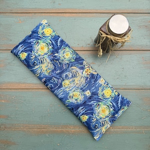 Puede incluir: Una almohada para los ojos de color azul y amarillo con un dise&ntilde;o de remolino que recuerda a la Noche estrellada de Van Gogh. La almohada est&aacute; hecha de tela y est&aacute; rellena de semillas de lino y lavanda.
