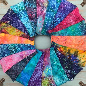 May include: A collection of colorful fabric scraps arranged in a circle, showcasing a variety of patterns and designs. The fabrics are primarily blue, green, and orange with intricate floral and geometric motifs.