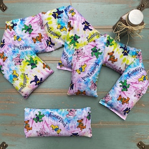 May include: Five tie-dye fabric neck pillows with the words "Grateful Dead" printed on them. The pillows are in various shades of purple, blue, green, and yellow.