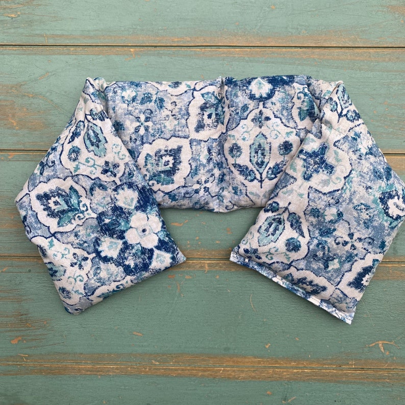 May include: A blue and white patterned neck wrap or heating pad. The fabric has a paisley design.