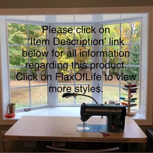 May include: A white sewing machine with a black foot pedal and a black lamp on a light brown table. The machine is in front of a window with a view of trees. The text on the machine reads "SINGER". The text on the window reads "Please click on 'Item Description' link below for all information regarding this product. Click on FlaxOfLife to view more styles."