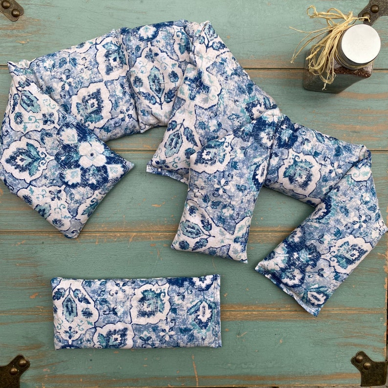 May include: A set of four blue and white patterned fabric neck pillows. The pillows are designed to be used as a neck wrap for comfort and relaxation.