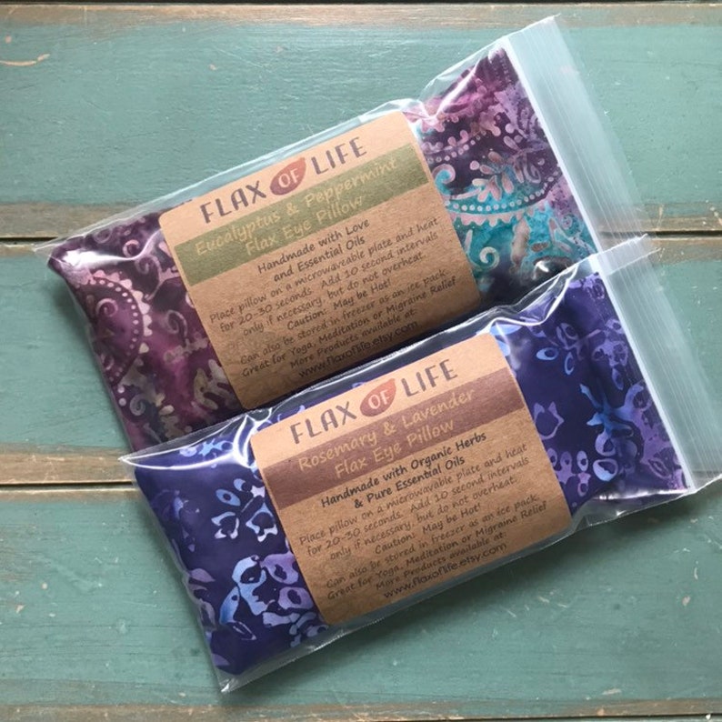 May include: Two purple and blue flax eye pillows in clear plastic bags. The bags have labels that read "Flax of Life" and list the ingredients and instructions for use. The labels are printed on brown paper.