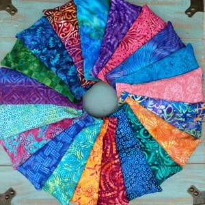May include: A collection of 18 colorful fabric-covered eye pillows arranged in a circle. The pillows are made of different fabrics with various patterns and colors, including blue, green, purple, pink, and orange.
