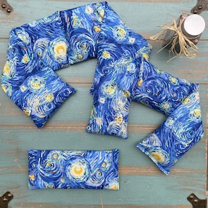 May include: A set of four blue and yellow neck pillows with a swirling starry night pattern. The pillows are made of fabric and are filled with rice. They are designed to be used as a neck wrap for pain relief.