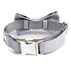 May include: A gray dog collar with a matching gray bow tie. The collar has a silver buckle.