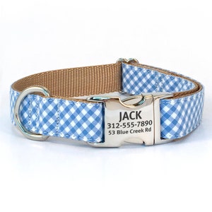 May include: A blue and white gingham dog collar with a brown nylon strap and a silver buckle. The buckle has the name "JACK" engraved on it, along with a phone number and address.