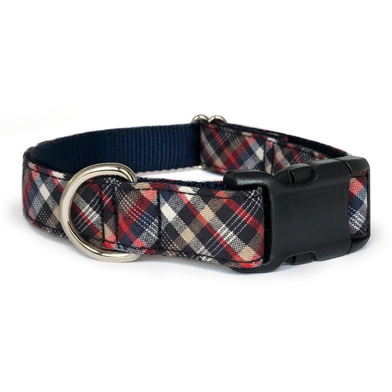 May include: A red, white, and blue plaid dog collar with a black buckle and a silver D-ring.