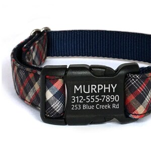 May include: A black and red plaid dog collar with a black buckle. The buckle has the name "MURPHY", phone number "312-555-7890", and address "253 Blue Creek Rd" engraved on it.