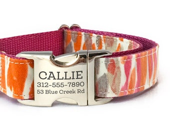 Puede incluir: Un collar de perro rosa y blanco con un diseño estampado naranja y gris. El collar tiene una hebilla plateada con el nombre "CALLIE", el número de teléfono "312-555-7890" y la dirección "53 Blue Creek Rd" grabados en él.