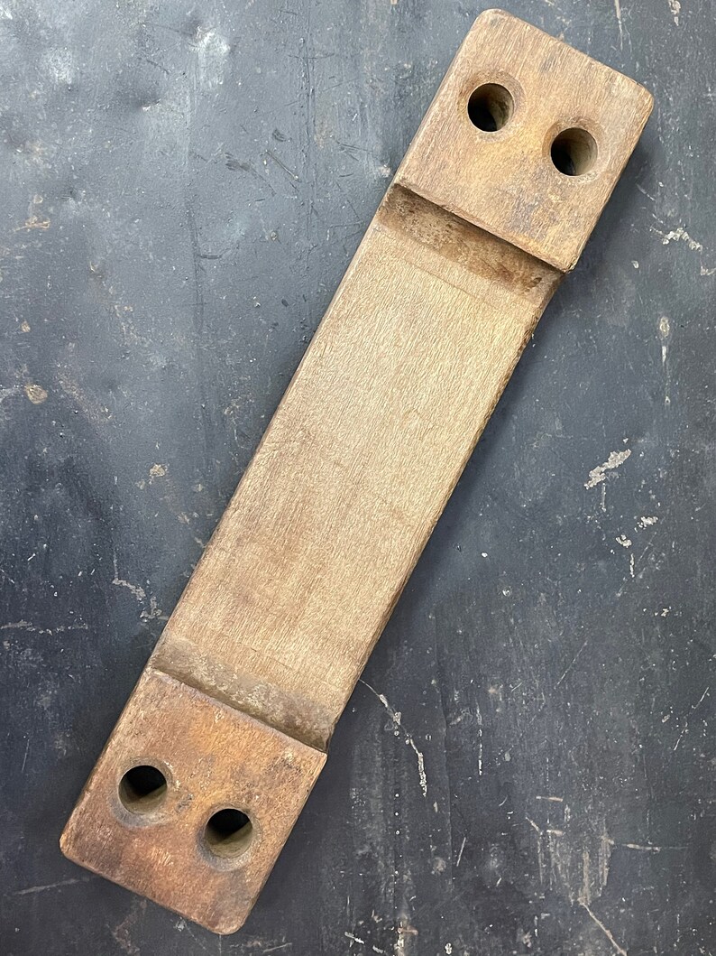 May include: A wooden block with two holes on each end. The block is light brown and has a smooth surface.