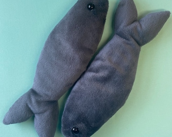 May include: Two gray plush fish toys with black eyes. The fish are sewn together at the tails.