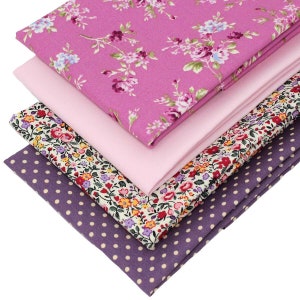 May include: A stack of four fabric squares in different patterns. The top square is pink with a floral print, the second is pink, the third is white with a floral print, and the bottom is purple with white polka dots.
