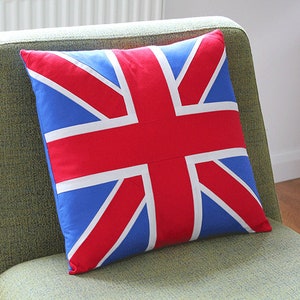May include: A red, white and blue cushion with the Union Jack flag design. The cushion is sitting on a green chair.