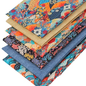 May include: A stack of six folded fabric pieces featuring various patterns including vibrant floral designs with orange, blue, and red, a solid tan textured fabric, a black fabric with small colourful flowers, and a solid blue denim-like textile.