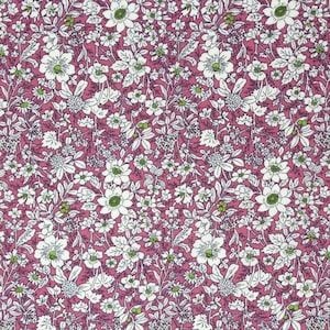 May include: A pink fabric with a white floral pattern. The fabric is covered in small white flowers with green centres and leaves.