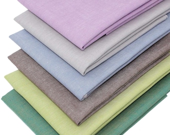 May include: A stack of six fabric swatches in various colors, including green, brown, blue, gray, and purple. The swatches are folded and arranged in a staggered pattern.