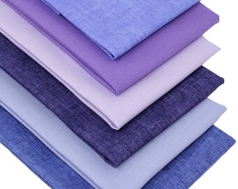 May include: A stack of six fabric squares in shades of purple and blue. The fabric has a subtle texture and a slightly faded look.