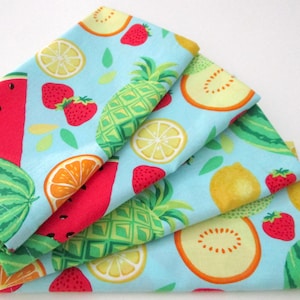 May include: Four blue fabric napkins with a colorful fruit print. The print features watermelon, pineapple, lemons, oranges, and strawberries.