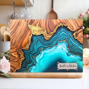May include: A blue and gold abstract design chopping board with the text "Amelia's Kitchen" in a gold frame.