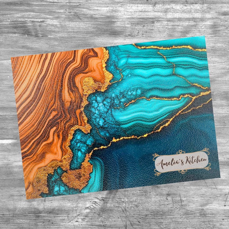 May include: Abstract art kitchen trivet with a blue, teal, and gold design. The trivet has a wood-like texture on one side and a smooth surface on the other. The trivet is decorated with gold accents and has the text "Amelia's Kitchen" in a gold frame.