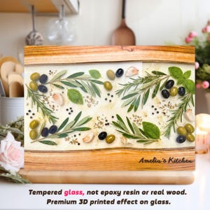 Può includere: Un tagliere rettangolare con cornice in legno e superficie in vetro. Il vetro è decorato con olive, erbe, aglio e spezie. Le parole "Amelia's Kitchen" sono stampate in basso a destra. Il testo in basso dice "Vetro temperato, non resina epossidica o vero legno."