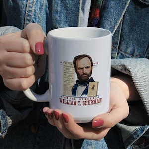 May include: White ceramic mug featuring a portrait of Major General William T. Sherman, a historical figure, holding a document. The mug has red stars and the text "OFFICIAL" and "MAJOR GENERAL WILLIAM T. SHERMAN" printed on it.