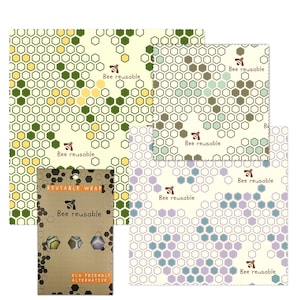 May include: A set of three reusable food wraps with a honeycomb pattern. The wraps are in green, blue, and purple colors. The wraps are made of beeswax, organic cotton, and tree resin. The wraps are eco-friendly and reusable. The packaging includes the text "Bee reusable" and "ECO FRIENDLY ALTERNATIVE".