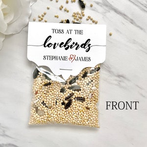 May include: A small clear plastic bag filled with birdseed. The bag has a white label with the text "Toss at the lovebirds Stephanie & James".