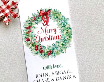 May include: A white gift tag with a green and red watercolor wreath with a red bow and the text "Merry Christmas". The text "with love, JOHN, ABIGAIL, CHASE & DANIKA" is printed below the wreath.