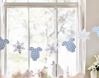 May include: A decorative garland featuring alternating paper cutouts of light blue and white gingham patterned baby onesies and white snowflakes strung together on a thin white cord, creating a repeating pattern of onesies and snowflakes.
